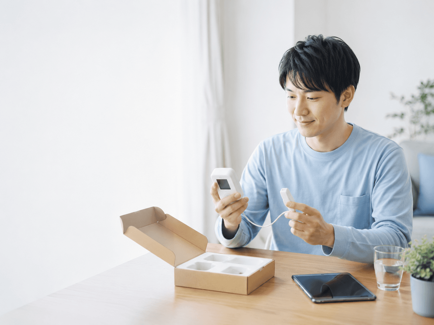 タブレットの案内を見ながら自宅で検査キットを準備する男性