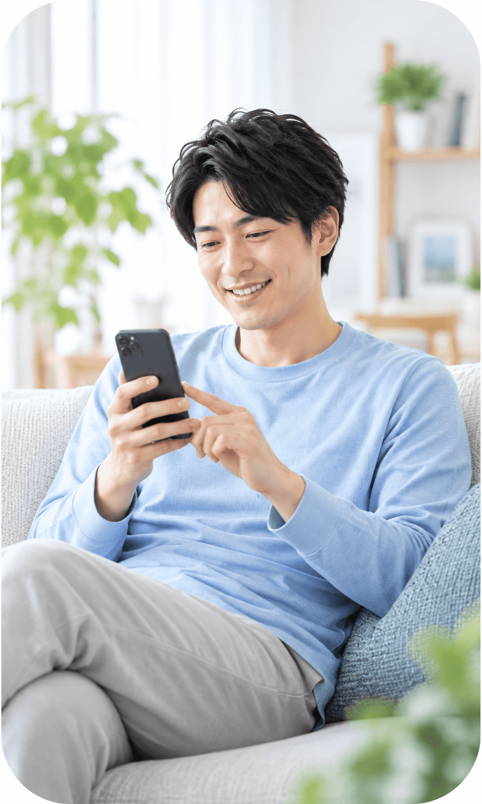 自宅のソファでスマートフォンを操作する男性